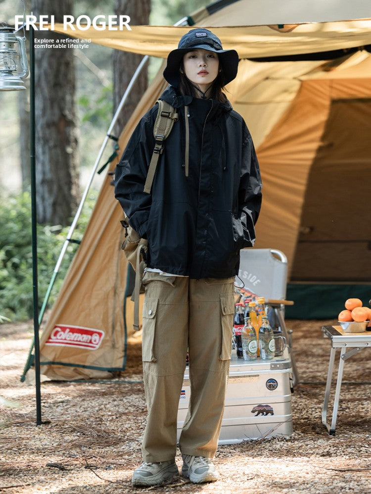 Load image into Gallery viewer, Person camping outdoors with a tent and cooler, wearing a black jacket and beige pants.