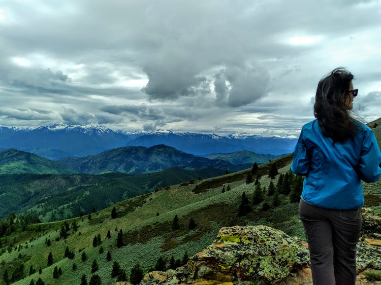 Woman in blue jacket standing on top of large hill