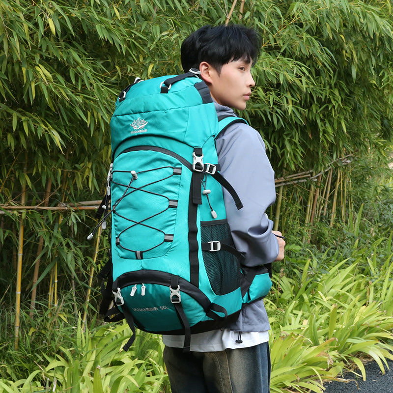 Load image into Gallery viewer, Person wearing a large teal backpack in a natural setting with greenery.
